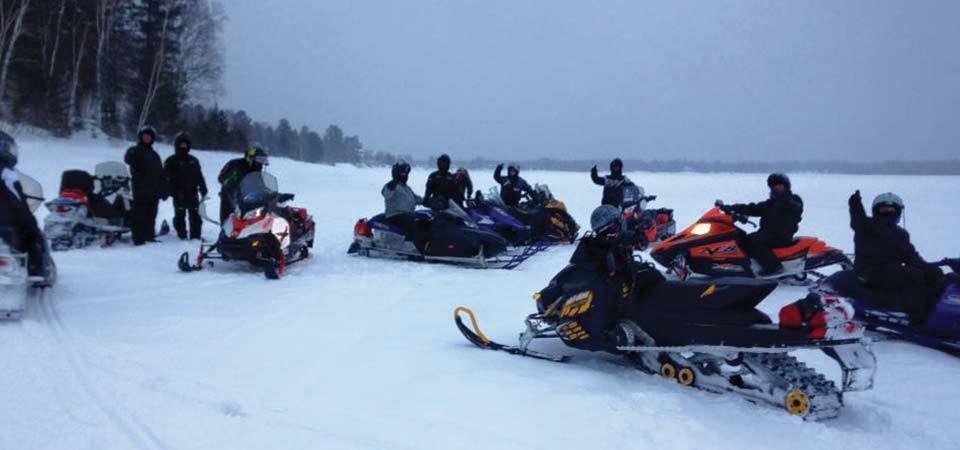 Groupe de motoneigistes heureux sur un lac gelé et eneigé